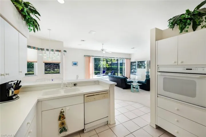 Kitchen featuring a peninsula, white appliances, light countertops, a ceiling fan, and open floor plan