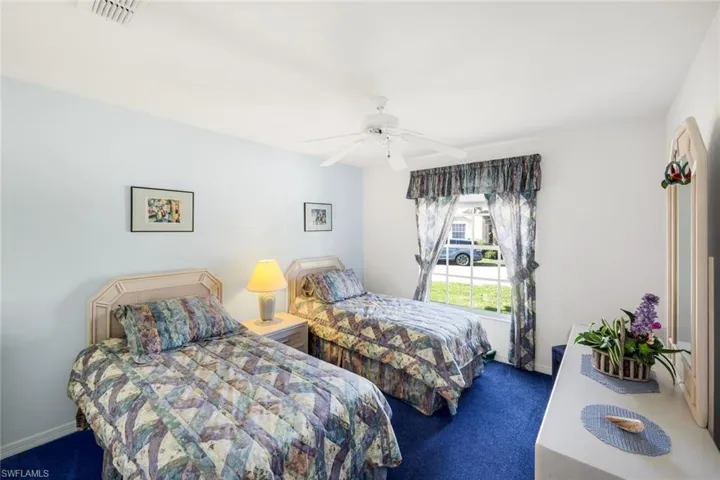 Bedroom with dark carpet and a ceiling fan