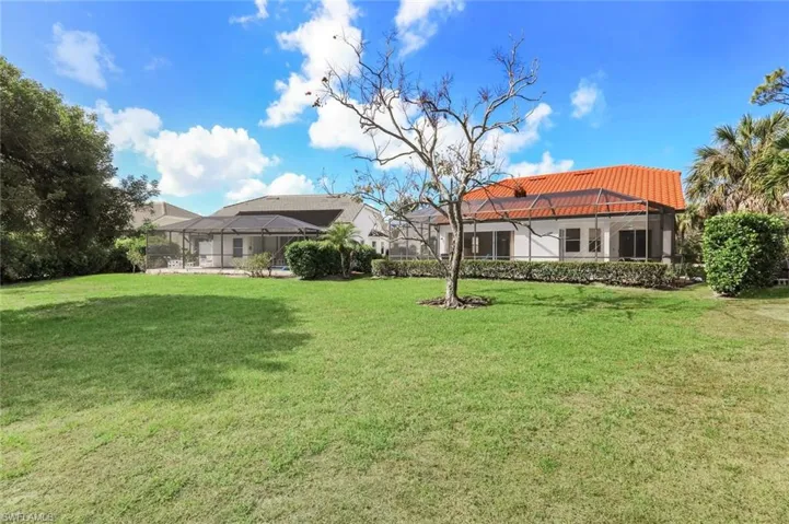 View of grassy yard with a lanai and a sunroom