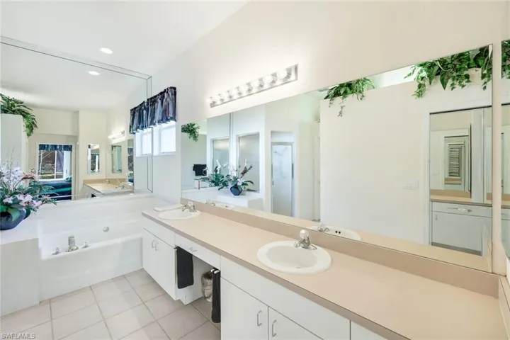 Full bathroom featuring double vanity, a bath, light tile patterned floors, and recessed lighting