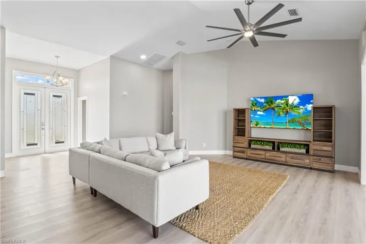 Living area featuring light wood finished floors, vaulted ceiling, a chandelier, and ceiling fan
