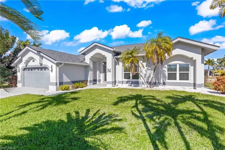 Single story home featuring stucco siding, an attached garage, a front yard, and driveway