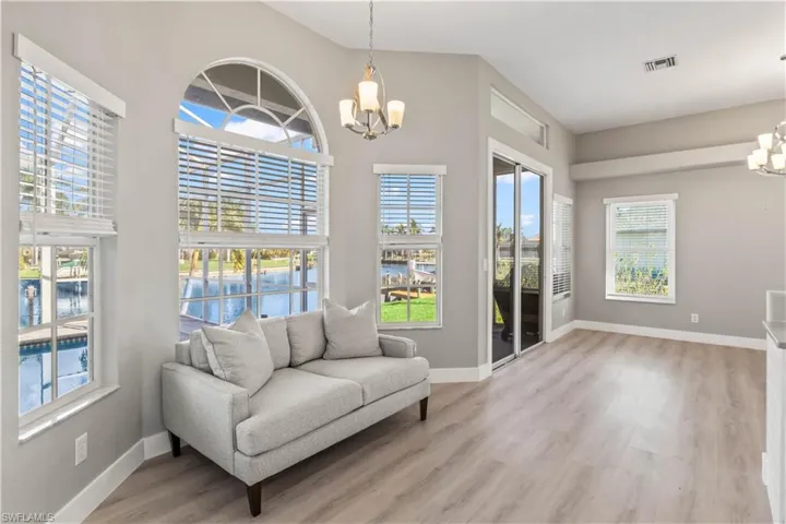 Sitting room with a chandelier, a water view, and light wood-style flooring