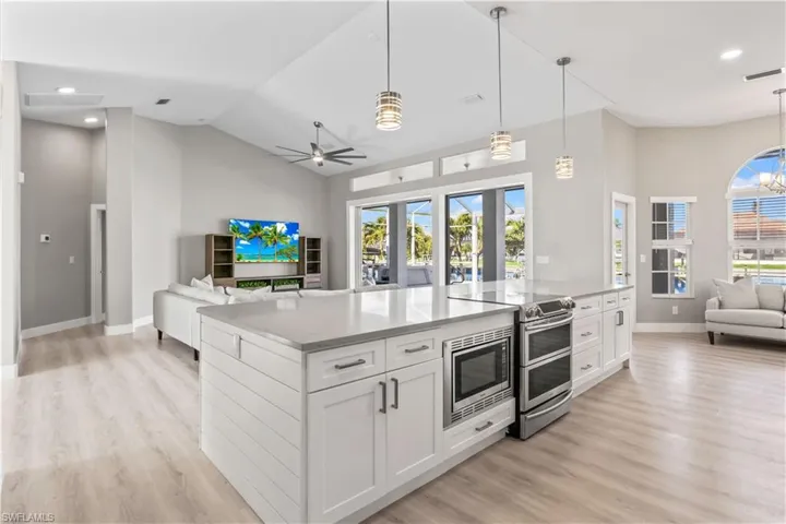 Kitchen featuring open floor plan, white cabinets, hanging light fixtures, a spacious island, and recessed lighting