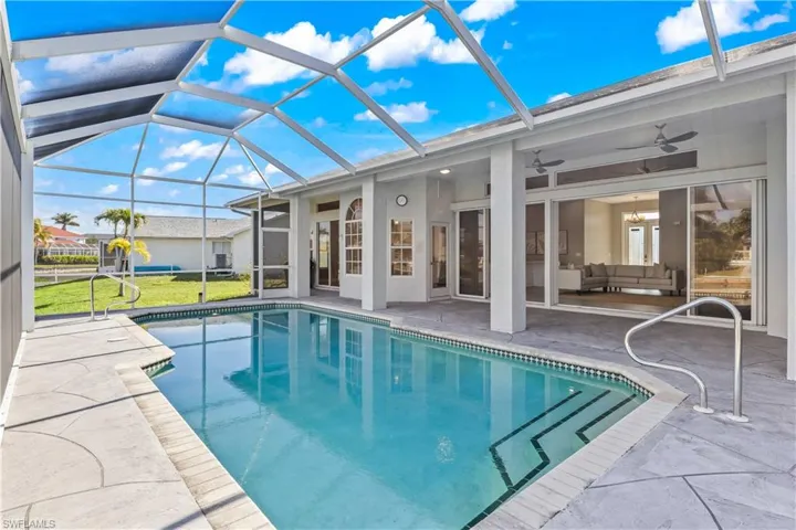 Swimming pool featuring a sunroom, a patio area, glass enclosure, and a lawn