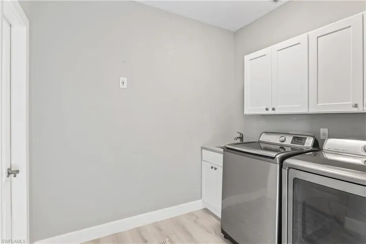 Washroom with cabinet space, washer and dryer, and light wood-style floors