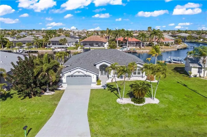 View of front facade featuring driveway, a residential view, a water view, and a garage