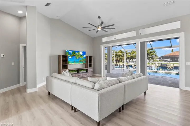 Living room with a sunroom, high vaulted ceiling, ceiling fan, and light wood-style flooring