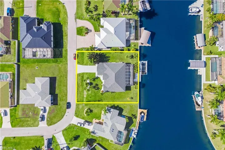 Aerial perspective of suburban area with a nearby body of water and property boundaries highlighted