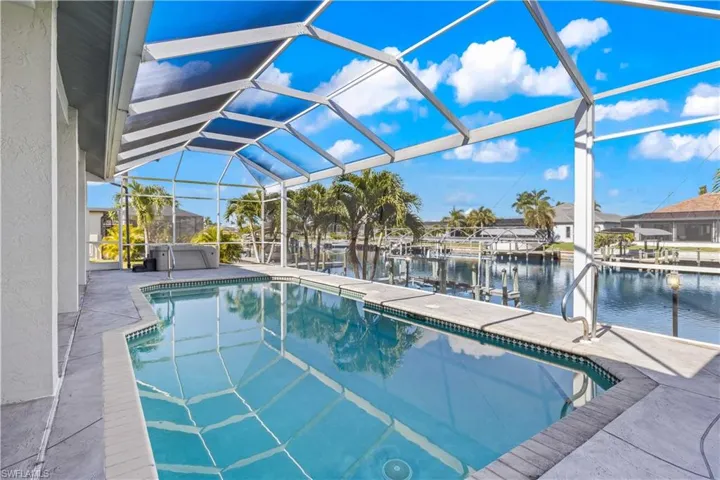 Swimming pool featuring a sunroom, boat lift, a water view, a patio area, and a lanai
