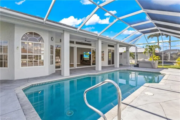 Outdoor pool with a sunroom, a lanai, a patio area, and a hot tub