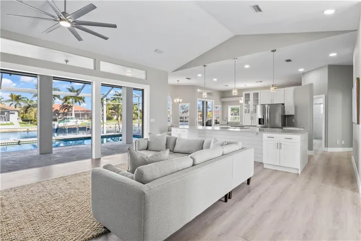 Living area with light wood-style floors, a chandelier, recessed lighting, ceiling fan, and high vaulted ceiling
