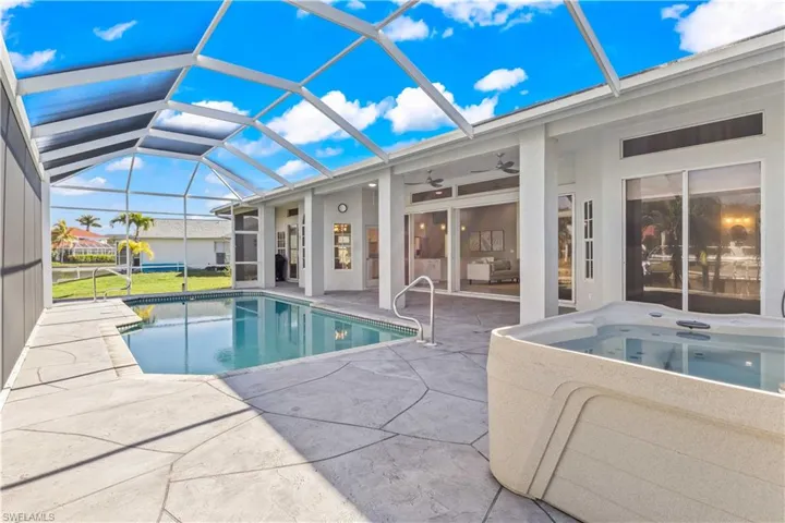 Swimming pool with a sunroom, a patio area, glass enclosure, and a hot tub
