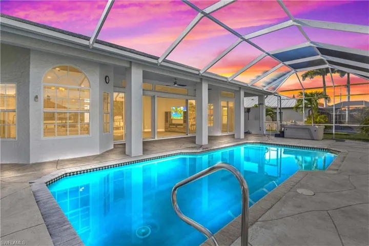 Outdoor pool featuring glass enclosure, a sunroom, a patio area, and a hot tub
