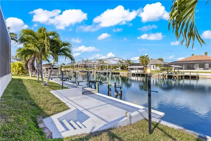 Dock area with a yard, a water view, boat lift, and a residential view