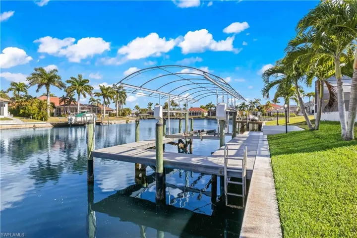 Dock featuring a water view, boat lift, a residential view, and a yard