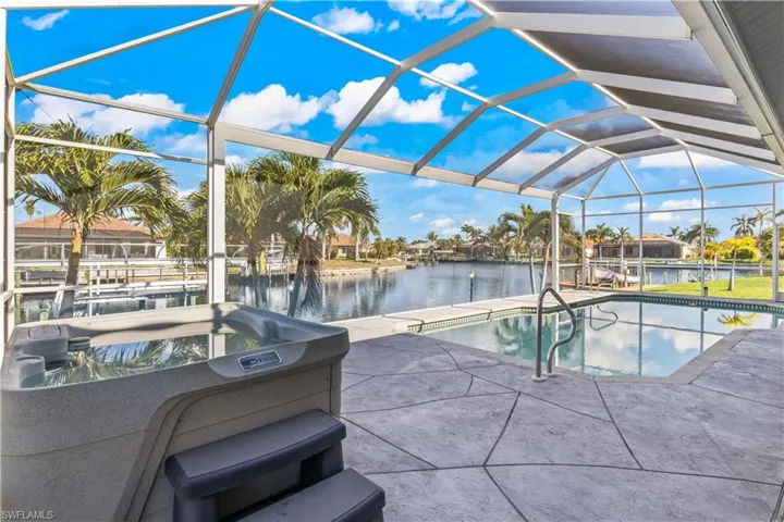 Swimming pool featuring a sunroom, glass enclosure, a patio, a water view, and boat lift