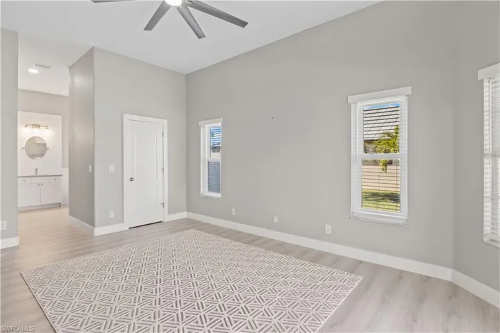Unfurnished bedroom with multiple windows, light wood-style floors, a ceiling fan, and a closet