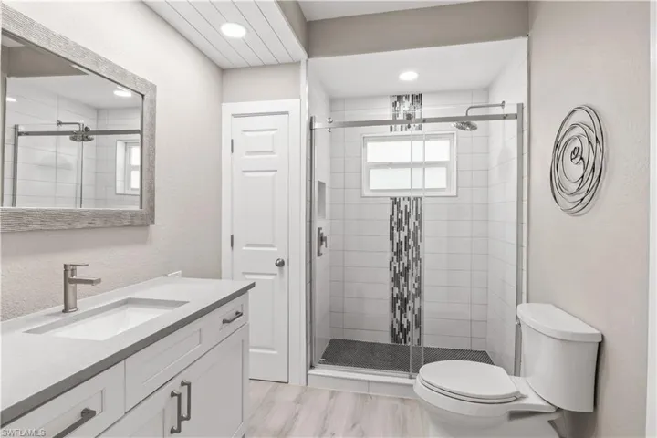 Bathroom featuring vanity, a shower stall, and a textured wall