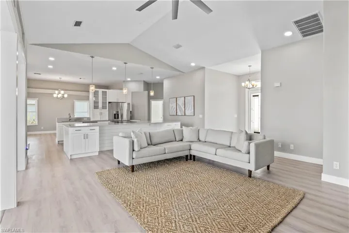Living room featuring a chandelier, recessed lighting, lofted ceiling, light wood finished floors, and ceiling fan