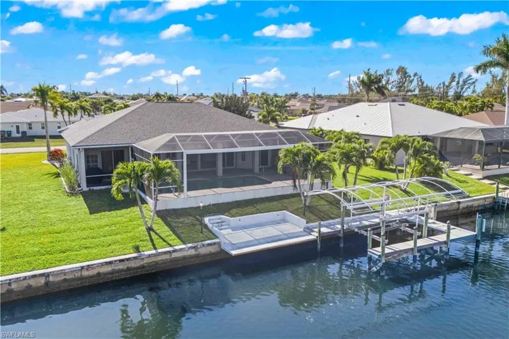 Rear view of property with a lanai, a yard, a sunroom, a water view, and boat lift