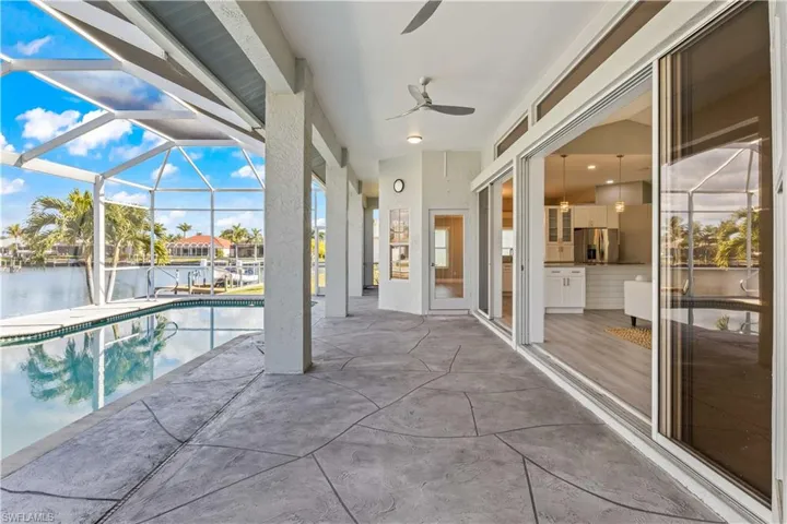 Outdoor pool with a patio area, a sunroom, glass enclosure, and a water view
