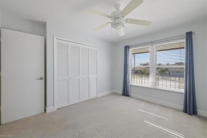 Unfurnished bedroom with light colored carpet, a closet, and a ceiling fan