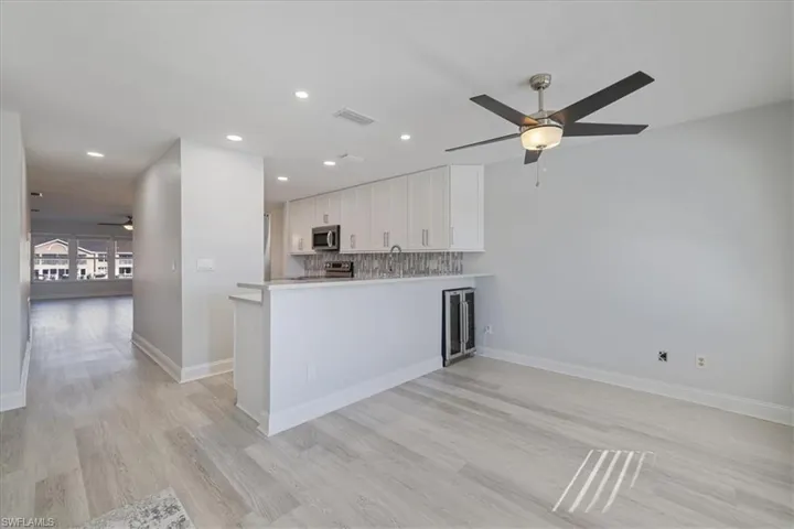 Kitchen featuring a ceiling fan, white cabinets, a peninsula, recessed lighting, and decorative backsplash