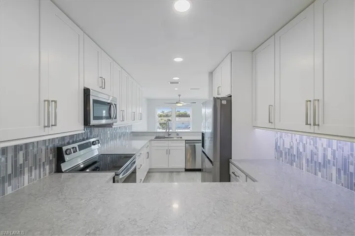Kitchen featuring stainless steel appliances, white cabinets, recessed lighting, tasteful backsplash, and ceiling fan