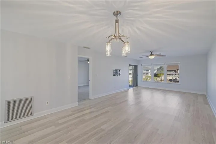 Unfurnished living room with ceiling fan, a chandelier, and light wood finished floors