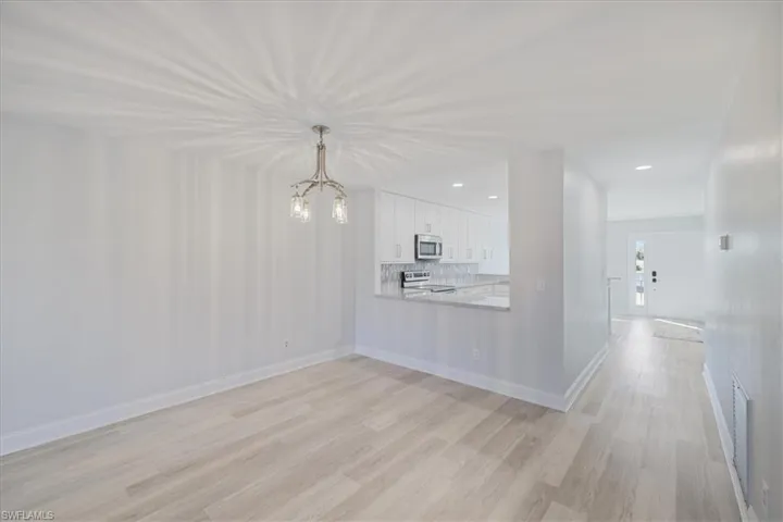 Unfurnished living room featuring light wood-type flooring and suspended lighting