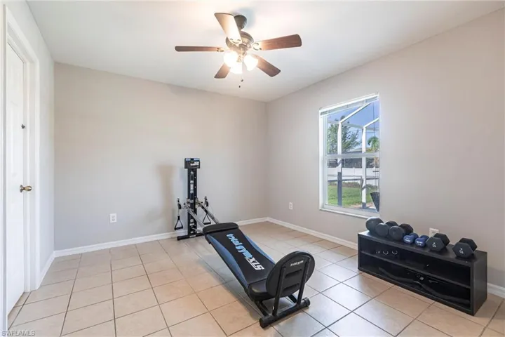 Workout area with light tile patterned floors and a ceiling fan