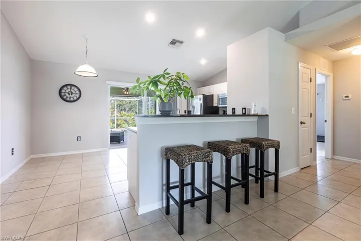 Kitchen with appliances with stainless steel finishes, light tile patterned floors, white cabinetry, a kitchen breakfast bar, and lofted ceiling