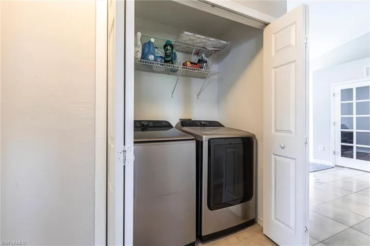 Laundry room with separate washer and dryer and light tile patterned floors