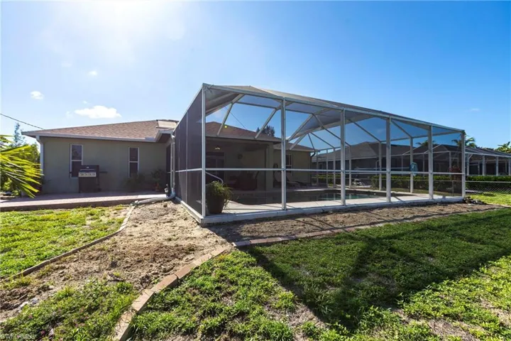 Rear view of house featuring a patio, stucco siding, an outdoor pool, and glass enclosure