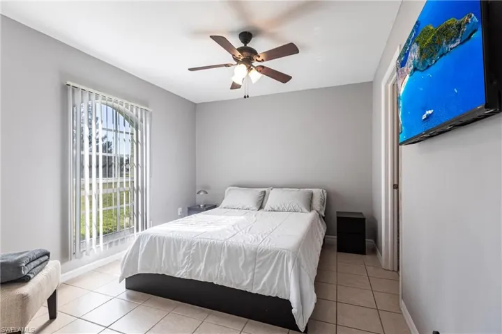 Bedroom featuring multiple windows, light tile patterned floors, and ceiling fan