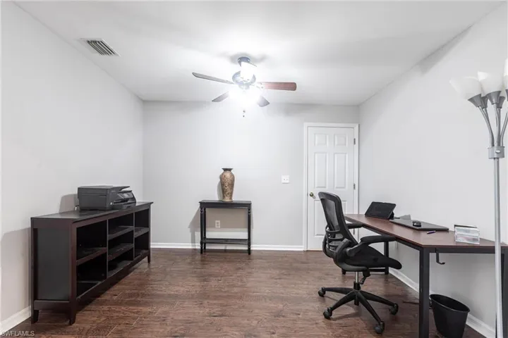 Office space with dark wood-style floors and a ceiling fan
