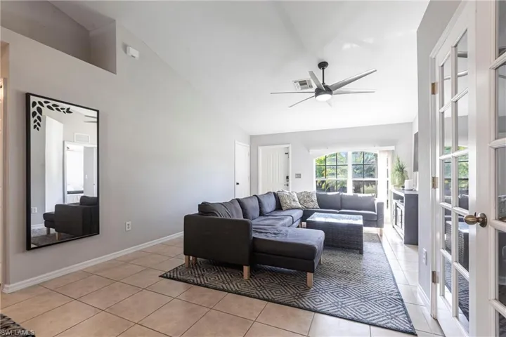 Living room featuring high vaulted ceiling, light tile patterned flooring, a ceiling fan, and french doors