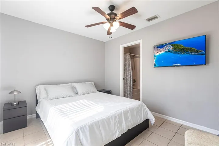 Bedroom featuring light tile patterned flooring, ceiling fan, and ensuite bath