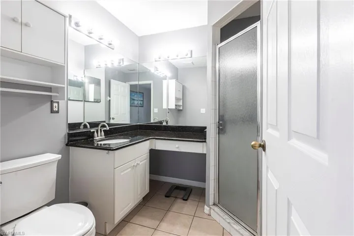 Bathroom featuring vanity, tile patterned floors, and a shower stall