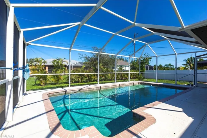 View of pool featuring glass enclosure and a patio