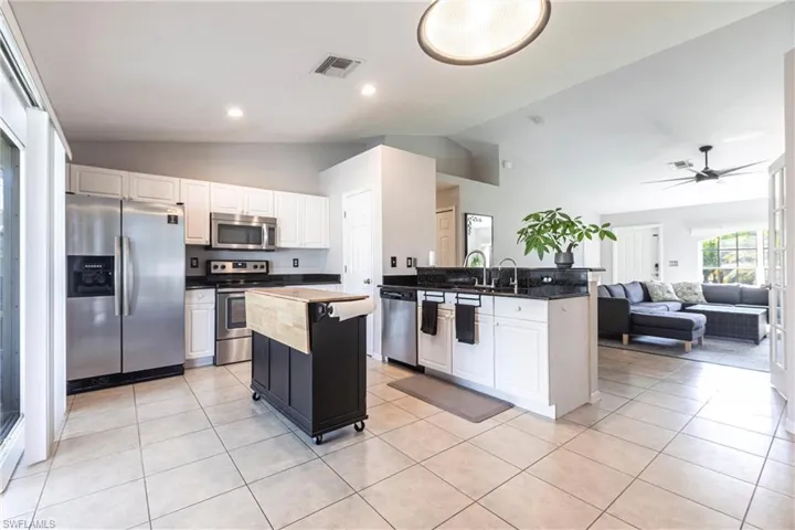 Kitchen featuring appliances with stainless steel finishes, lofted ceiling, ceiling fan, a peninsula, and open floor plan