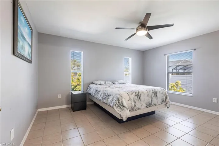 Bedroom featuring multiple windows, light tile patterned flooring, and ceiling fan