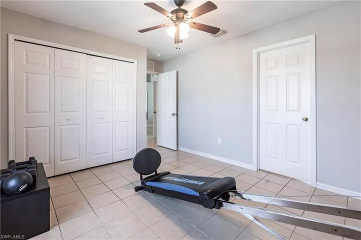 Workout area with light tile patterned floors and ceiling fan