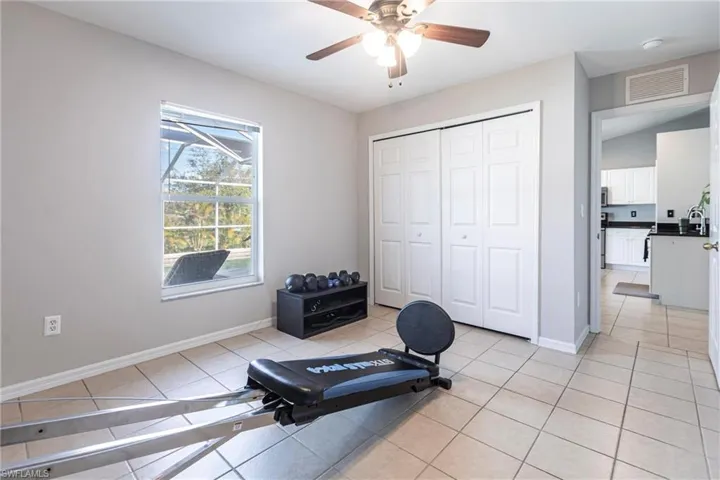 Workout room with light tile patterned flooring and a ceiling fan
