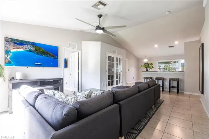 Living area with light tile patterned floors, lofted ceiling, and a ceiling fan