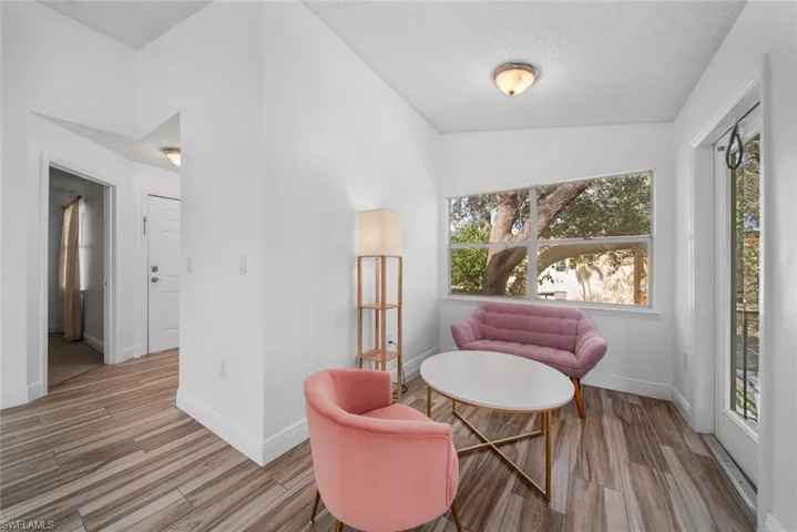 Living area with a textured ceiling, vaulted ceiling, and light wood-type flooring