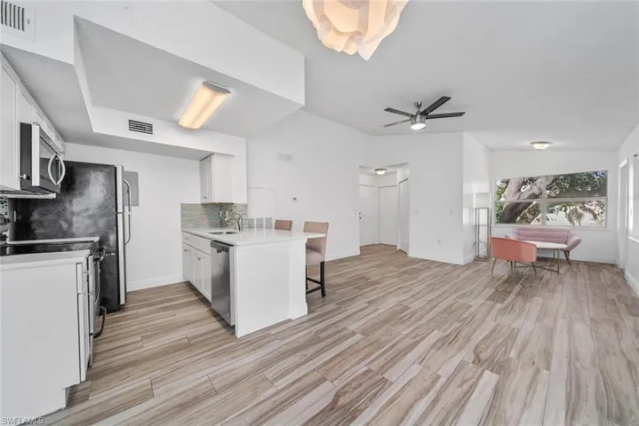 Kitchen with decorative backsplash, appliances with stainless steel finishes, white cabinetry, and sink