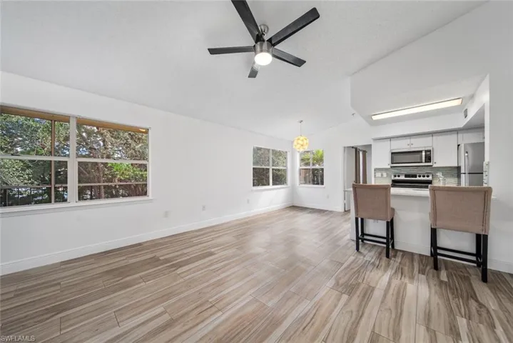 Living room featuring a textured ceiling, light hardwood / wood-style floors, ceiling fan, and lofted ceiling