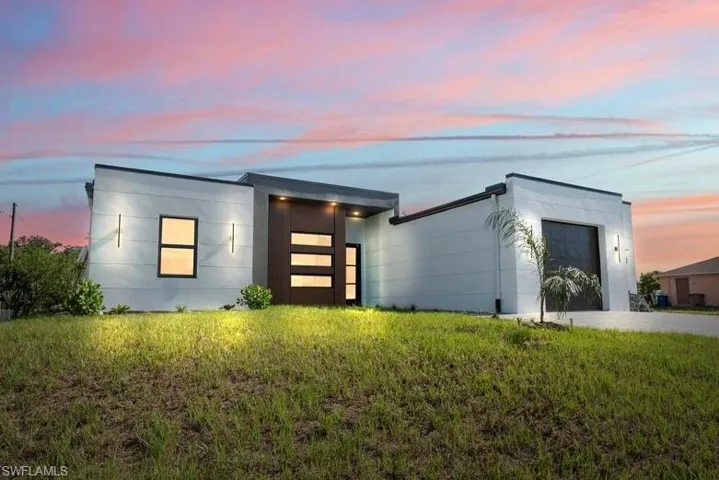 Modern home featuring an attached garage and a front lawn